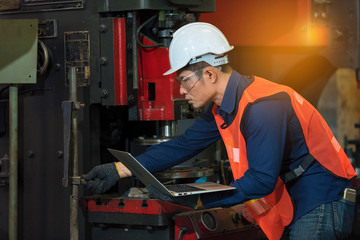 worker with computer laptop.Factory worker in a hard hat is using a laptop computer with an...