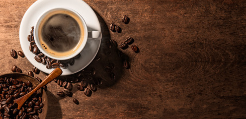 Cup of coffee and coffee beans on wooden table