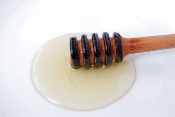 
honey dipper on a white plate with natural honey.