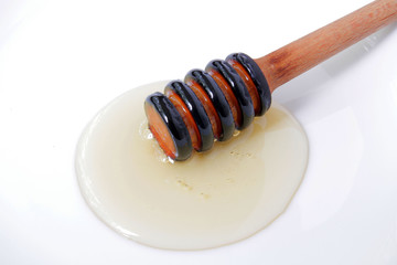 
honey dipper on a white plate with natural honey.