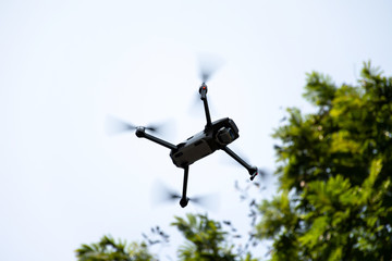 Drone quad copter flying with the tree background.