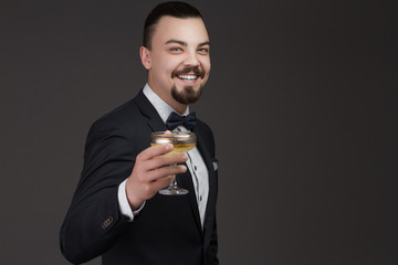 Portrait of a handsome young man with a glass in his hand dressed in a stylish classic suit