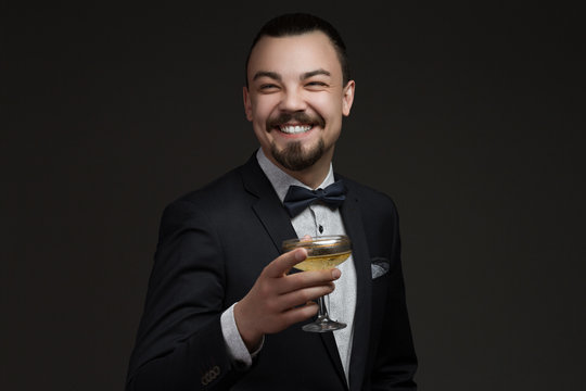 Portrait of a handsome young man with a glass in his hand dressed in a stylish classic suit