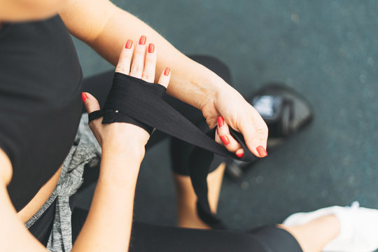 Crop photo of young athletic girl shakes boxing bandages on her hands before training
