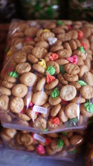 pastries with colorful topings wrapped in plastic in a cake shop