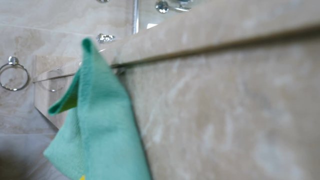 Cleaning service, close-up Housemaid from hotel staff in uniform and protective gloves cleaning large bathroom with wipe using liquid detergent cleaner. disinfecting surfaces from dirt, bacteria or