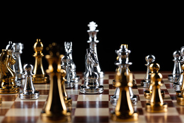 Gold and silver chess figures on chessboard