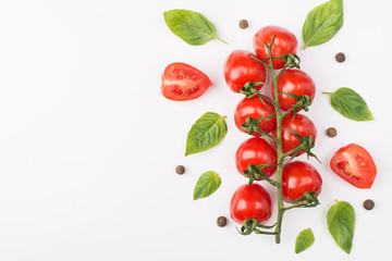 Top above overhead view photo of a bunch of cherry tomatoes surrounded with peppercorns and basil leaves isolated on white background