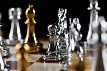 Gold and silver chess figures on chessboard