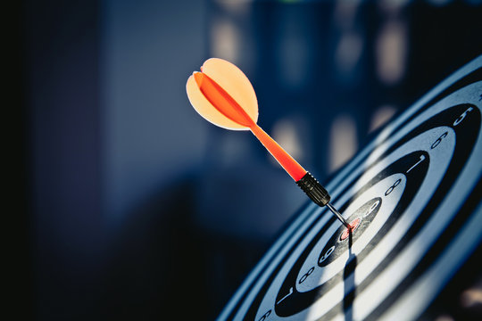 Bullseye(bull's-eye) or dart board has dart arrow hitting the center of a shooting target for business targeting and and marketing goal concepts.