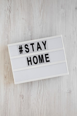 'Stay home' words on a lightbox on a white wooden background, top view. Overhead, from above, flat lay.