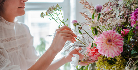 Female professional florist prepares the arrangement of wild flowers.