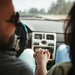 Young joyful couple traveling by car. Man and woman sitting in car. Tourism lifestyle, love and travel concept