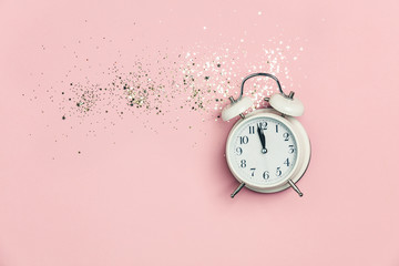 Creative composition with alarm clock and golden stars confetti on pink background