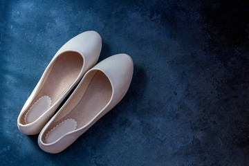 Urban women shoes: beige flats, slip-on. Casual summer footwear on dark background. Women or teenage fashion. Flat lay, top view, copy space for text. Shopping and sale concept.