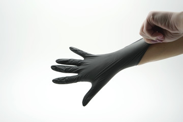 Close-up of a hand that is wearing a medical, latex, nitrile, black glove on a white background.