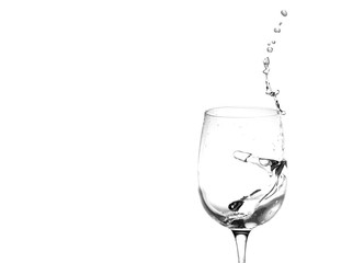 Water in a wine glass. Splash of liquid on a white background. Isolated object. Spray. Copy space for text. Selective focus.