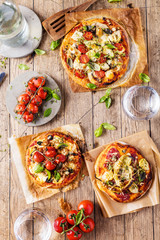 Fototapeta na wymiar gourmet pizza with tomatoes, olives and basil leaves on wooden table