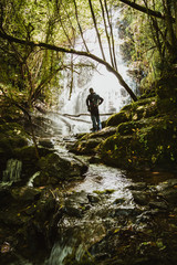 Obraz premium Man front of a waterfall in the forest