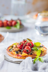 gourmet pizza with tomatoes, olives and basil leaves on wooden table