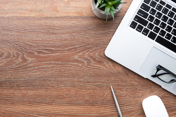 Wood office desk table with laptop computer and office supplies. Top view with copy space, flat lay.
