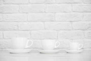 white mugs on a white table against a white brick wall