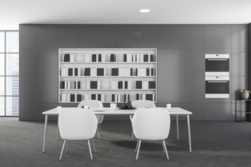Fototapeta na wymiar Grey dining room interior with bookcase and ovens