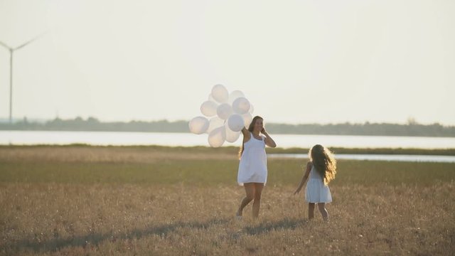 mother with daughter and balloons walk in nature