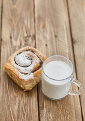 Fototapeta na wymiar Basket of homemade buns with jam, served on old wooden table with cup of milk