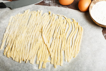 Homemade pasta step by step cooking process. Step 6. pasta cut from dough on cooking paper, flour, eggs, rolling pin.
