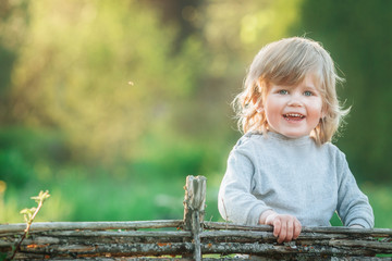 A pretty blond boy with long hair and blue eyes 3 years old smiles in nature. space for text. Copy space. Selective focus