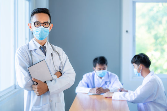 Asian medical team wearing medical masks technology network team meeting concept. Doctor at a table discussing a patients records working, Online medical treatment, New normal