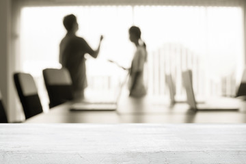 Empty wooden desk space over blurred office or meeting room background. Product display.