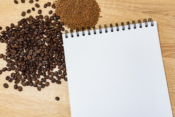 coffee grains on a wooden table, instant coffee on the surface, background for advertising, notebook for ideas, menu in a coffee shop