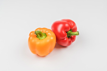 Two bell peppers orange and red on a light background.