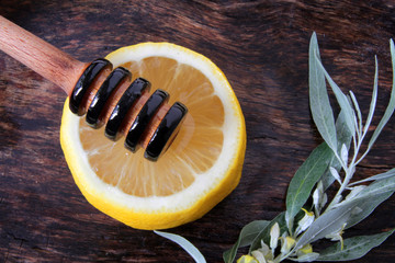 
honey dipper on a slice of lemon with natural honey and herbs.