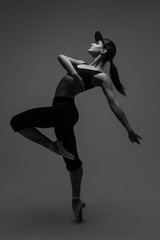 Elegant girl posing in ballet pointe shoes and a rapper cap