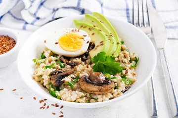 Breakfast oatmeal porridge with green herbs of mushrooms, boiled egg, avocado and flax seeds. Healthy balanced food.