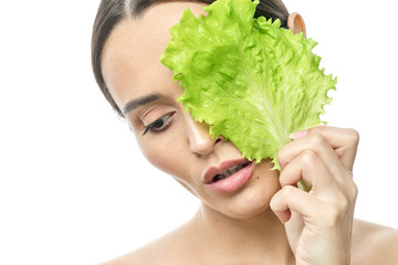 portrait of a girl with clean skin without makeup with a leaf of green salad