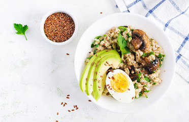 Breakfast oatmeal porridge with green herbs of mushrooms, boiled egg, avocado and flax seeds. Healthy balanced food. Top view, overhead,  copy space