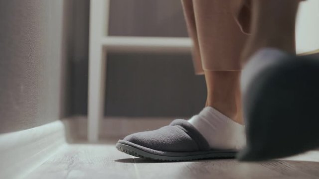 Woman getting out of bed, put on grey slippers