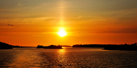 Beautiful sunset on the sea, islands and orange sky.