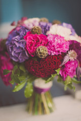 Beautiful wedding bouquet on a blurry blue background with maroon and purple flowers. Hydrangea, carnation. Wedding day. Bock (beer). Bride. Bride's bouquet. Wedding flowers.Wedding bouquet.