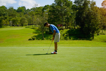 Golfer putting golf in a beautiful golf course in the evening with a sunset background in Thailand.
