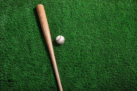 High Angle View Of Baseball Bat With Ball On Grassy Field