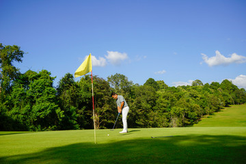 Golfer putting golf in a beautiful golf course in the evening with a sunset background in Thailand.