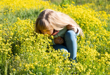 Cute girl sniffs yellow flowers in a summer meadow