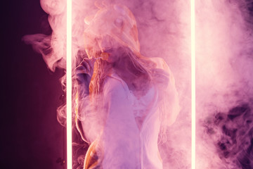 Beautiful girl in smoke posing in neon light