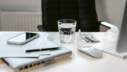 Workplace in the office. Desk businessman. A glass of water, pills and drops for the eyes as a symbol of illness, fatigue, coronavirus.