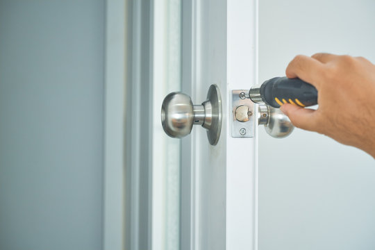 locksmith home service with silver handle and screwsriver on white door